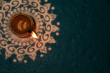 Teal background with a golden clay oil lamp for the Diwali Festival of Lights