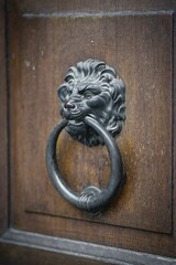 Vertical closeup of an old metallic door knob in shape of a lion head