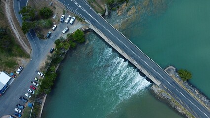 Aerial top shot of a bridge on a seascape with a road and cars