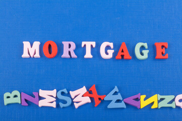 MORTGAGE word on blue background composed from colorful abc alphabet block wooden letters, copy space for ad text. Learning english concept.