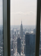 Fototapeta na wymiar Vertical shot of the Empire State Building seen through a window, New York, USA