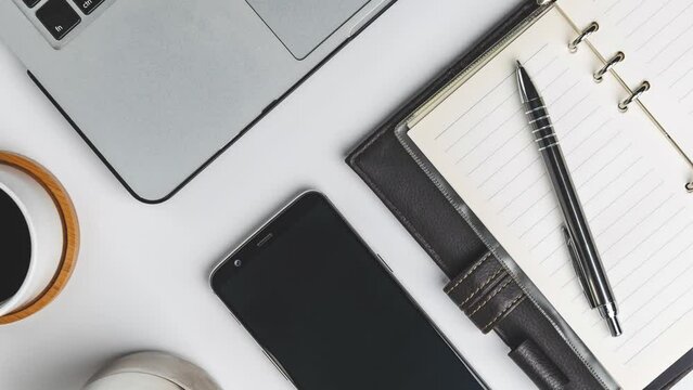 Coffee, phone, notebook with a pen on a white table, a concept of a working area