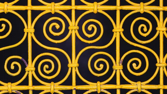 Closeup of a beautiful yellow fence against the dark wall