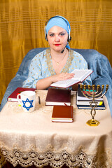 A Jewish woman in a kisui rosh headdress, a Torah teacher in headphones with a microphone, conducts...