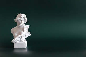 Marble head of young woman, ancient Greek goddess bust isolated on green background with space for text.