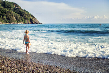 girl walking on the beach, looking on the sea