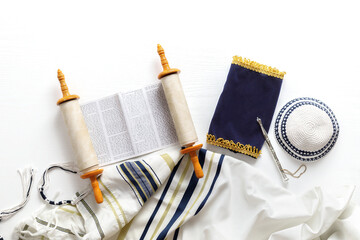 Torah scroll with a pointer, prayer shawl tallit and kippah on a light background - obrazy, fototapety, plakaty