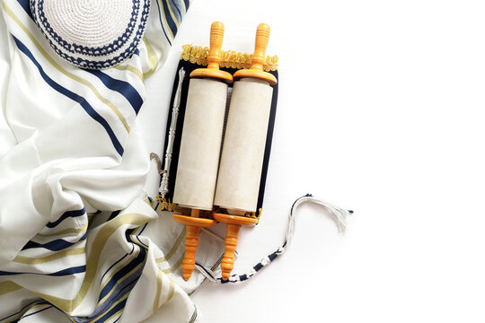 Torah scroll with a pointer, prayer shawl tallit and kippah on a light background
