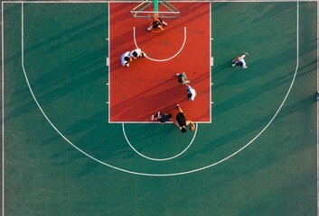 Aerial top view of a basketball court and young people playing the game © Zhou Chenxiao/Wirestock Creators