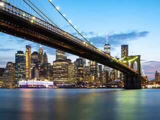 Illuminated Brooklyn Bridge with New York City skyline in he background in the United States