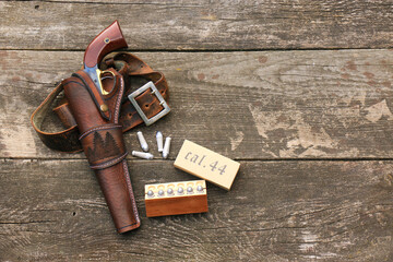 Black powder revolver in a leather holster with a leather strap and paper cartridges in a wooden...