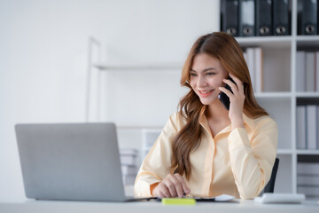 Happy beautiful smiling businesswoman talking on mobile phone whith laptop working in office.