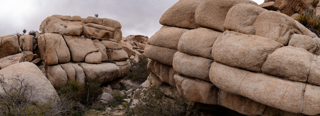 A natural boulder pile in the Mojave Desert provides a striking, unique landscape in a wide panorama. A cloudy sky suggests the photo was taken in winter or spring. © Levi Meir Clancy