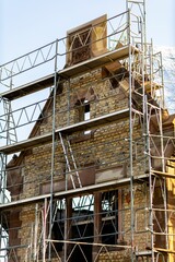 Vertical shot of an old masonry building covered in scaffolding