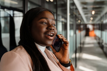 Young african american woman talking on cellphone at office corridor