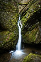 Vertical long exposure of the water falling down a mesmerizing creek fall through mossy rocks