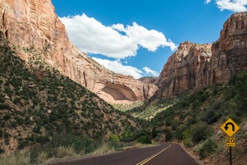 Long and narrow road leading to the mountains against a cloudy sky