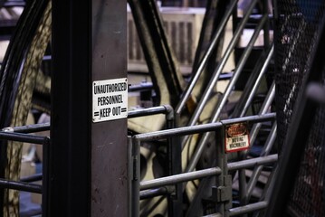 Inside of an industrial building with a warning sign on a metal pillar near the dangerous machine