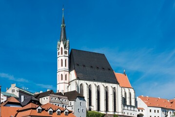 Church of St. Vitus surrounded by red roof buildings under a blue sky in Cesky Krumlov, Czechia