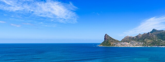 Panoramic shot Hout Bay with rugged coastal mountain and blue sea