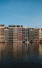 Vertical shot of colorful houses on the shore of a canal in Amsterdam, the Netherlands