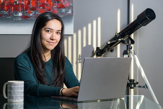 Asian woman at desk working on laptop in home office