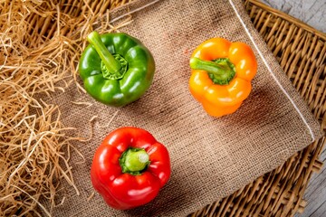 Top view of three colorful peppers on a piece of fabric on a table