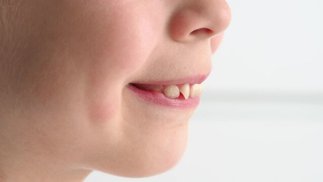 Beautiful childish smile close-up from the side. A girl with an angelic gentle smile. tender baby lips. Children's emotion