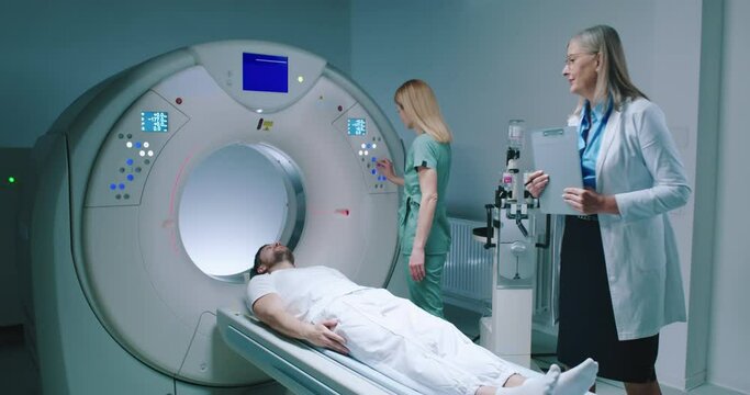 Man is lying down at TC scanner capsule. Medical pushes buttons and prerares for tomography examination. Female doctor checked process and goes out of room. Preparing for magnetic resonance imaging.