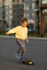 Fototapeta premium Little boy learning to skateboard at sunset