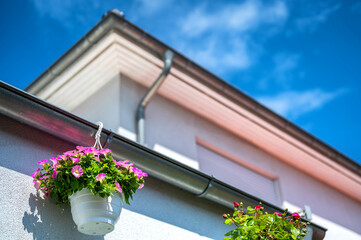 Dachentwässerung an einem Wohnhaus mit dekorativen Blumenampeln