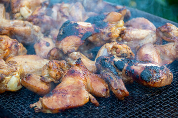 chicken drumsticks are grilled on a barbecue grill in the evening.