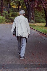 Vertical shot of an adult man seen from behind, walking in a park