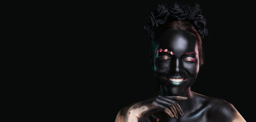 Beautiful woman with black paint on her body against dark background with space for text