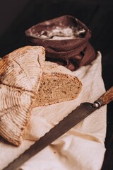 High-angle of freshly baked and sliced bread with flour and a knife on the table