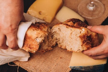 Man tearing the freshly baked Italian bread with cheese and a glass of wine on the table