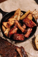 Vertical of tasty village potatoes and barbecue meat on the pan