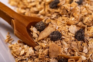 Close-up shot of a wooden spoon in a bowl filled with cereal with dried fruit