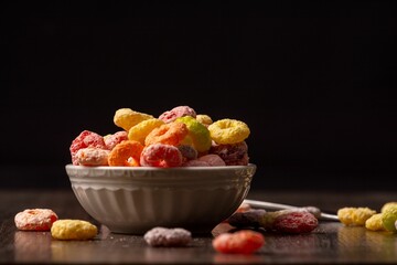 White plate with colorful cereal on a wooden table on a black background