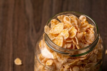 Glass jar filled with cereal flakes on a wooden surface