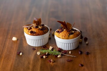 Wooden table with cranberry muffins on white plates