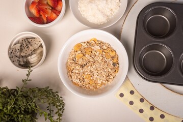 Top view of a table with bowls filled with cereals and strawberries for cooking cookies