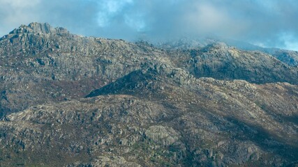 Fototapeta na wymiar Aerial shot of rocky peaks of a mountain range under the cloudy sky