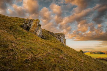 Fototapeta na wymiar Beautiful shot of a cloudy sunset sky over a rural hill with stone formations in Baden-Wurttemberg