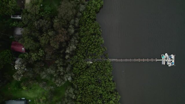 Drone shot over a pier in Hawkesbury River with green forest trees and rural houses in Australia