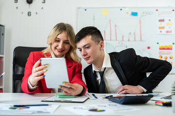 Businesspeople wotk together analyzing financial reports using laptop and tablet computer at office