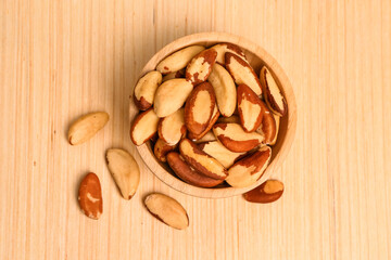 Bowl of delicious Brazil nuts on wooden background