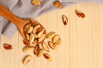 Spoon of tasty Brazil nuts on wooden background