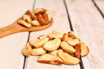 Heap of tasty Brazil nuts on light wooden background, closeup