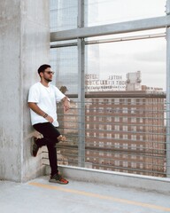 Young guy standing outside behind the window with the city in the background